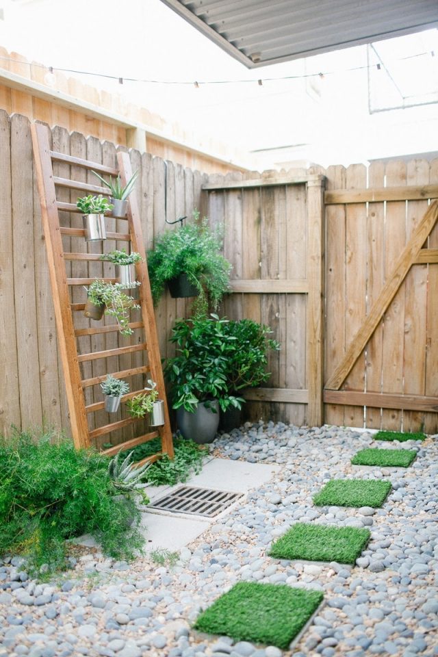 photo of a backyard with faux grass paver stones and vertical garden