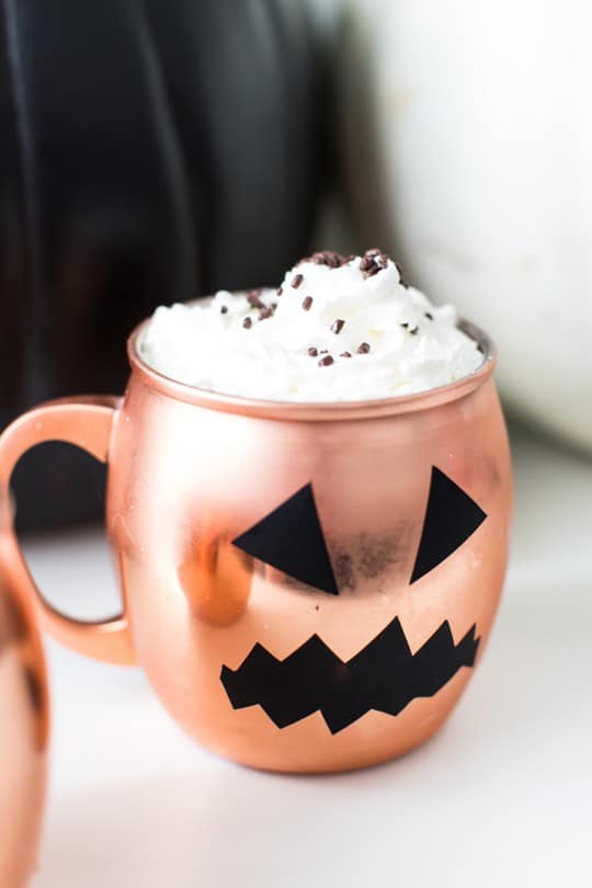 photo of a copper mug with pumpkin face decal and whipped cream