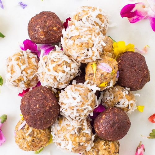 a mound of peanut butter balls with coconut flakes, cinnamon, and edible flowers