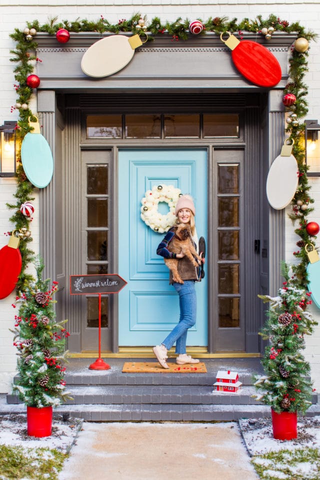 photo of a girl with a dog in front of outdoor christmas door decorations