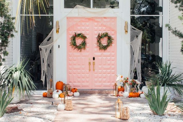 horizontal photo of a pink front door with halloween decorations