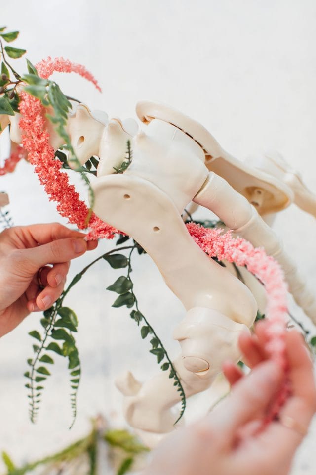 photo of stringing fake flowers onto a unicorn skeleton