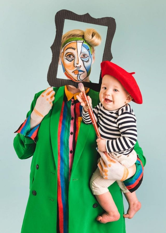 Photo of mother holding young child dressed as Picasso. Mother is dressed as a masterpiece.