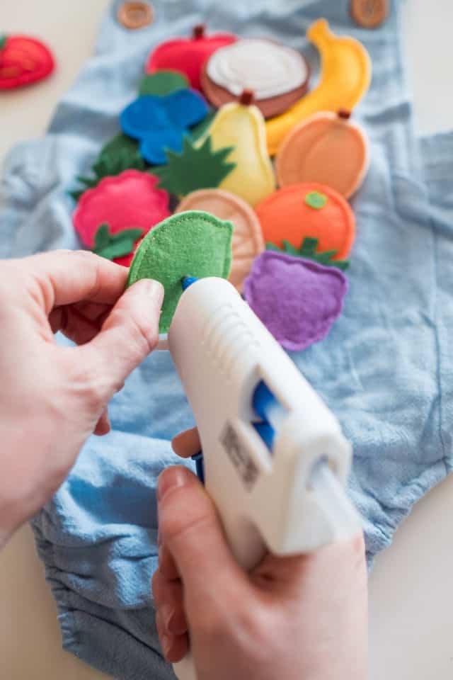 photo of felt fruit being glued onto a romper