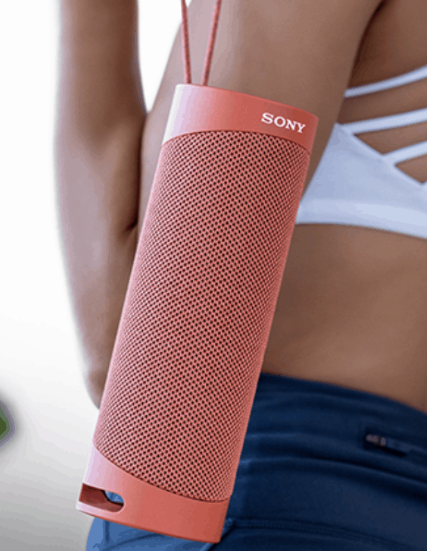 a coral red waterproof bluetooth speaker with string loop held by a woman for music lover 