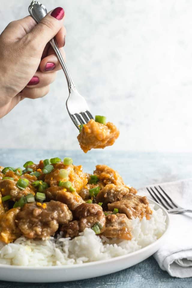 photo of someone taking a bite to the easy orange chicken dinner by top Houston lifestyle blogger Ashley Rose of Sugar & Cloth