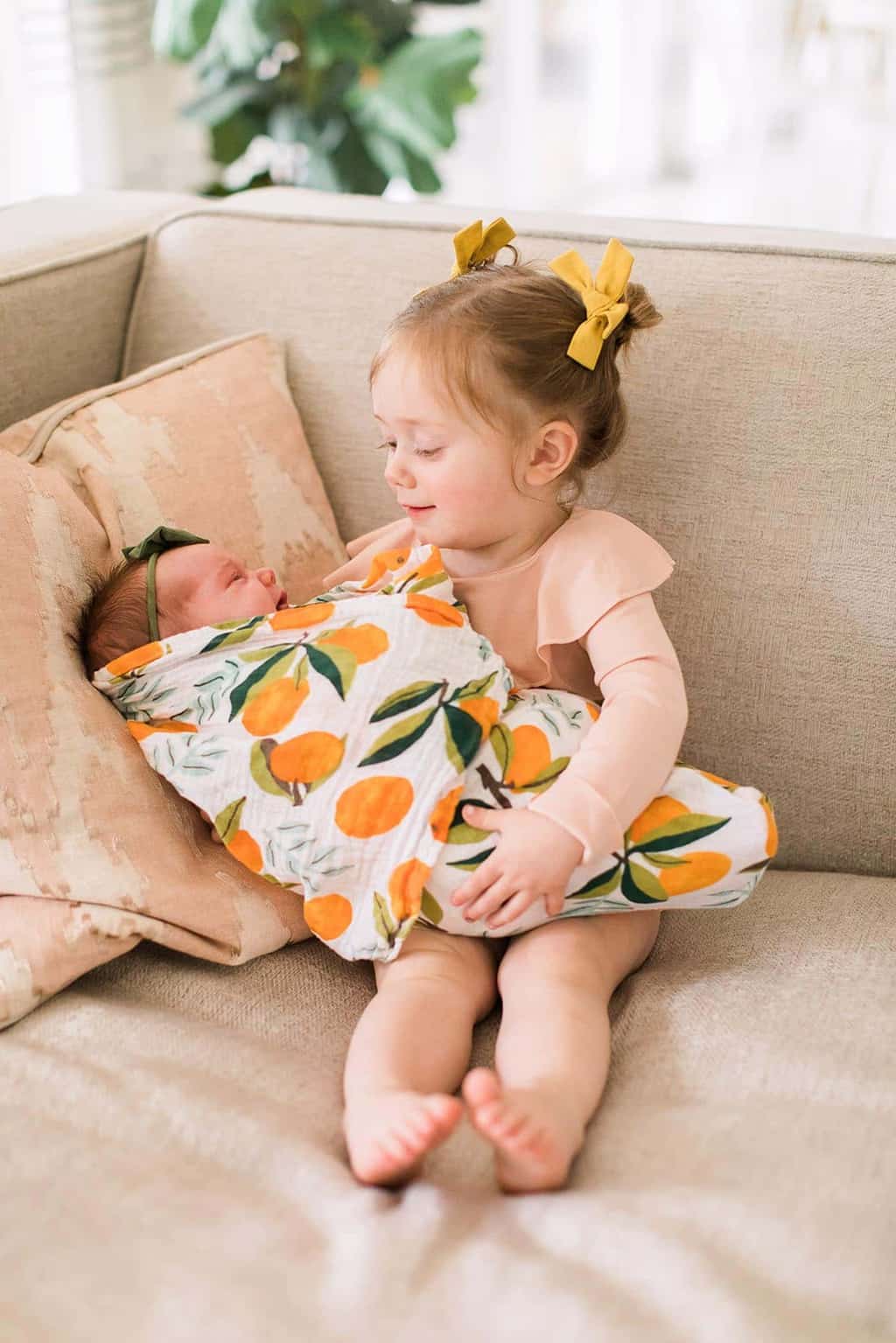 toddler girl holding new baby sister