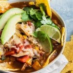 photo of a closeup of a loaded easy chicken tortilla soup topped with avocado and lime wedges by top Houston lifestyle blogger Ashley Rose of Sugar & Cloth
