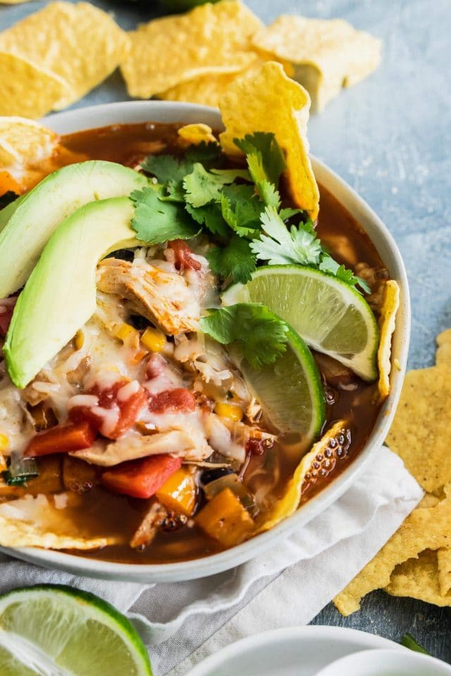 photo of a closeup of a loaded easy chicken tortilla soup topped with avocado and lime wedges by top Houston lifestyle blogger Ashley Rose of Sugar & Cloth