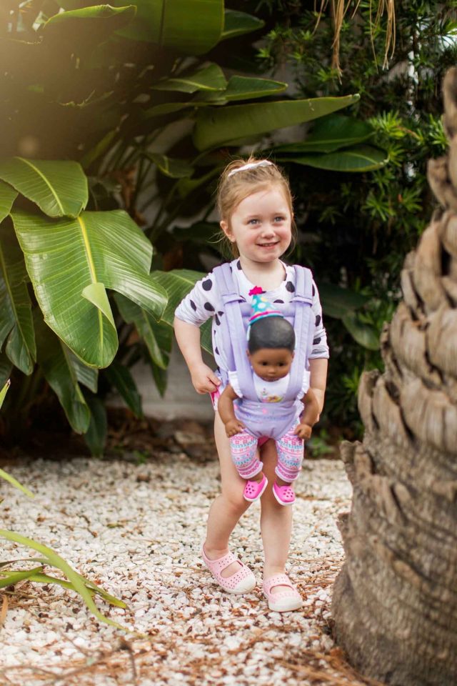 toddler girl and baby doll carrier