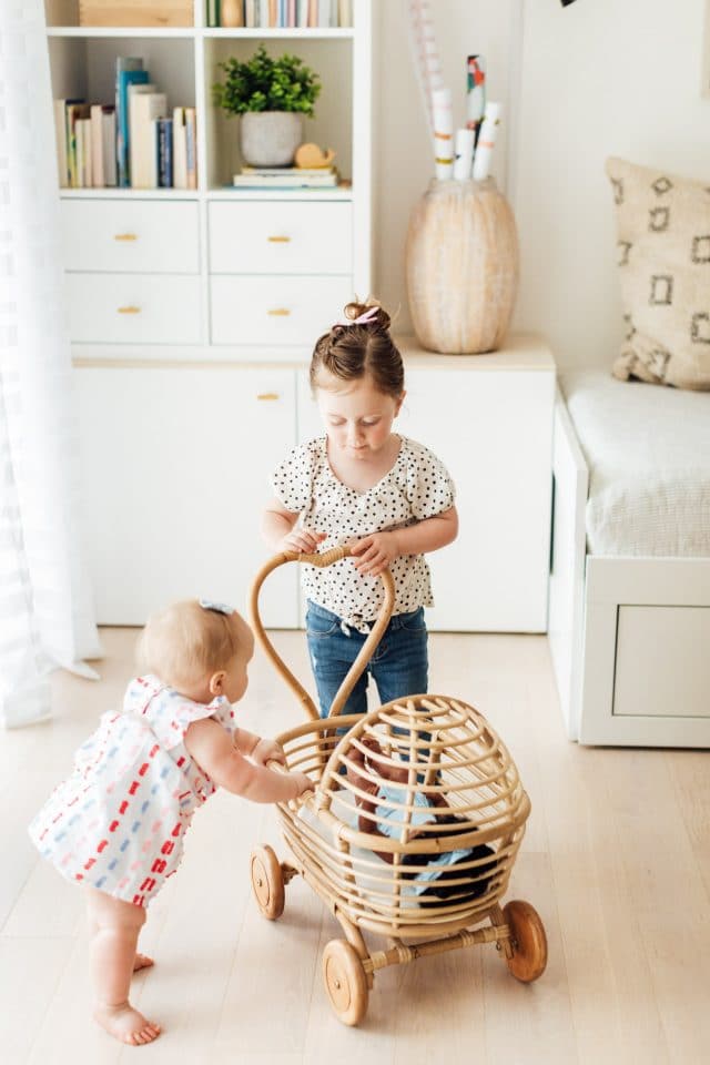 playroom ideas- little girls playing with a rattan doll cart