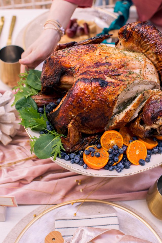 a close up of hands placing a turkey on a the thanksgiving table