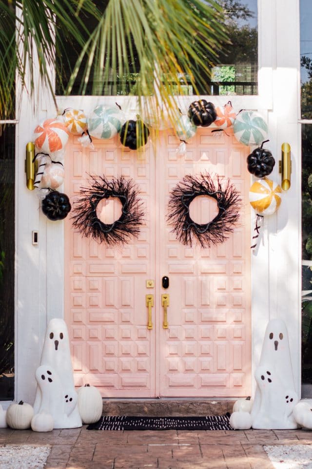 two black wreaths and a pink double door with ghost decorations