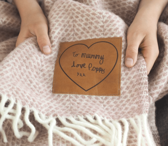 custom throw blanket with handwritten leather tag and a girls hand holding it - custom gifts for her