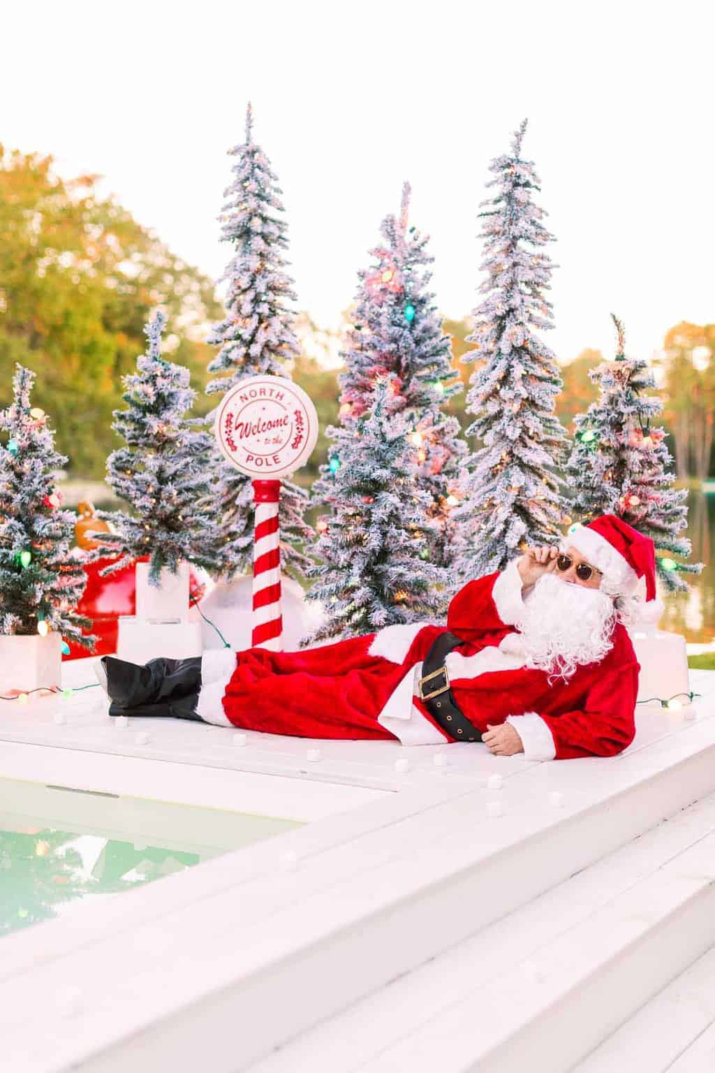 santa laying next to the pool with christmas trees