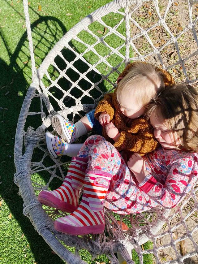 two little girls in a swing