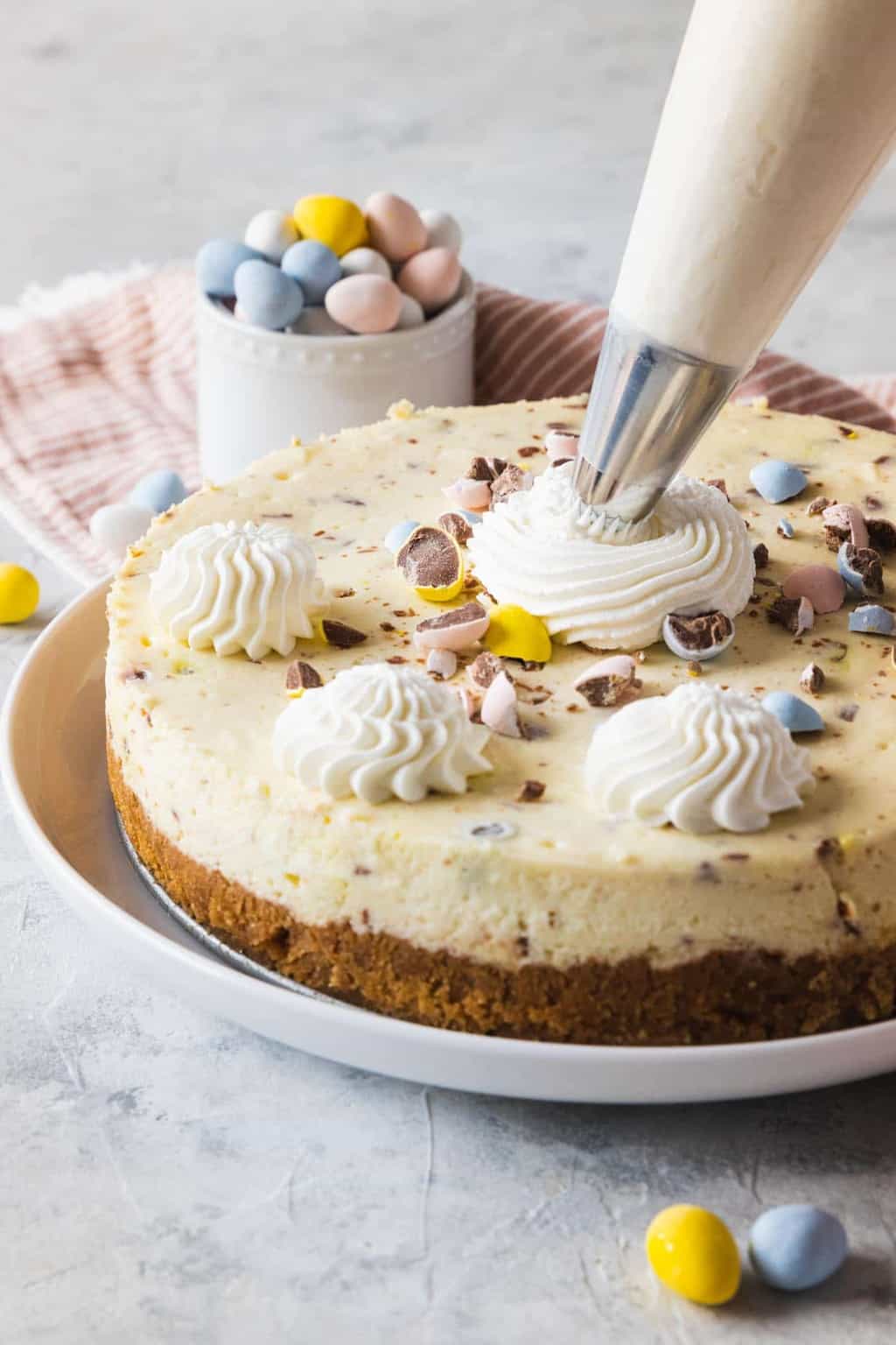 photo of the Easter Egg Cheesecake being decorated with whipped cream by top Houston lifestyle blogger Ashley Rose of Sugar & Cloth