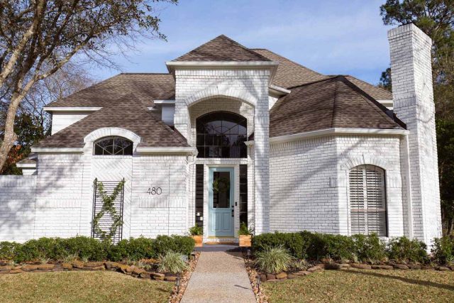 a horizontal photo of painted white exterior brick house