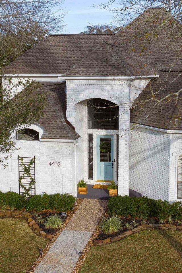 an angled drone photo of an exterior white house with limewash