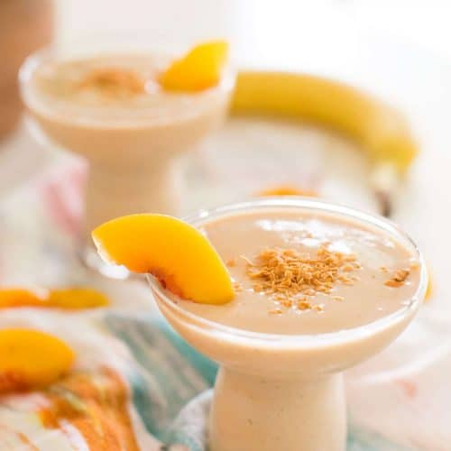 close up of a banana peach in a smoothie with a banana on a table