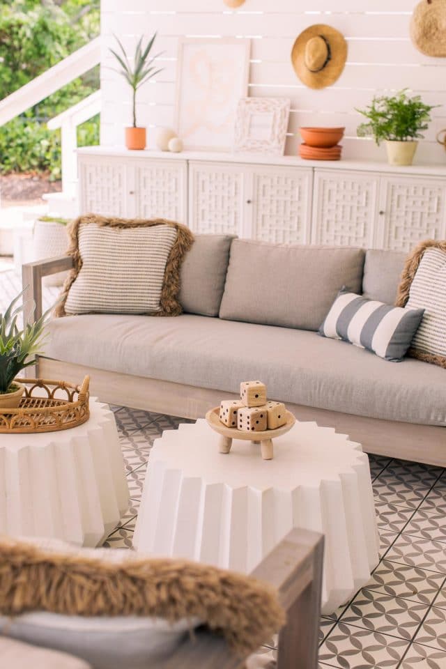 two white geometric concrete tables in front of an outdoor sofa