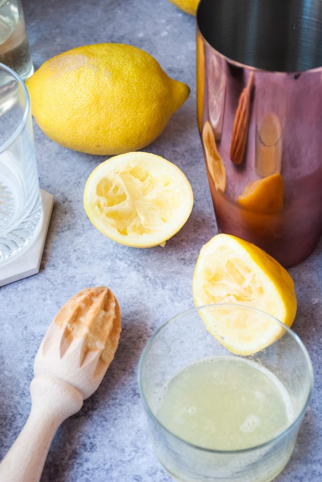 Amaretto Sour Ingredients - a photo of a freshly squeezed lemon placed inside a glass.