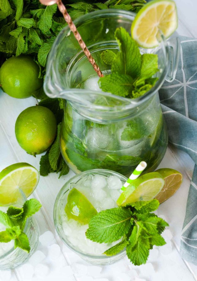 best mojito recipe pitcher -a top angled photo of a pitcher and a glassful of mojito surrounded by fresh limes