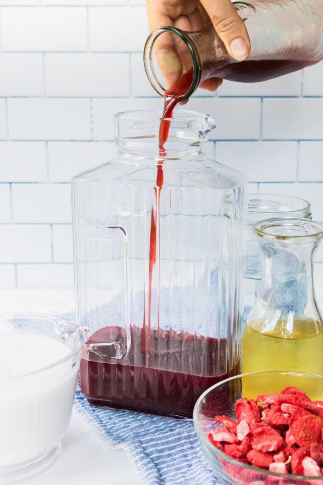 how to make a pink drink - a photo of a grape juice being poured in a pitcher