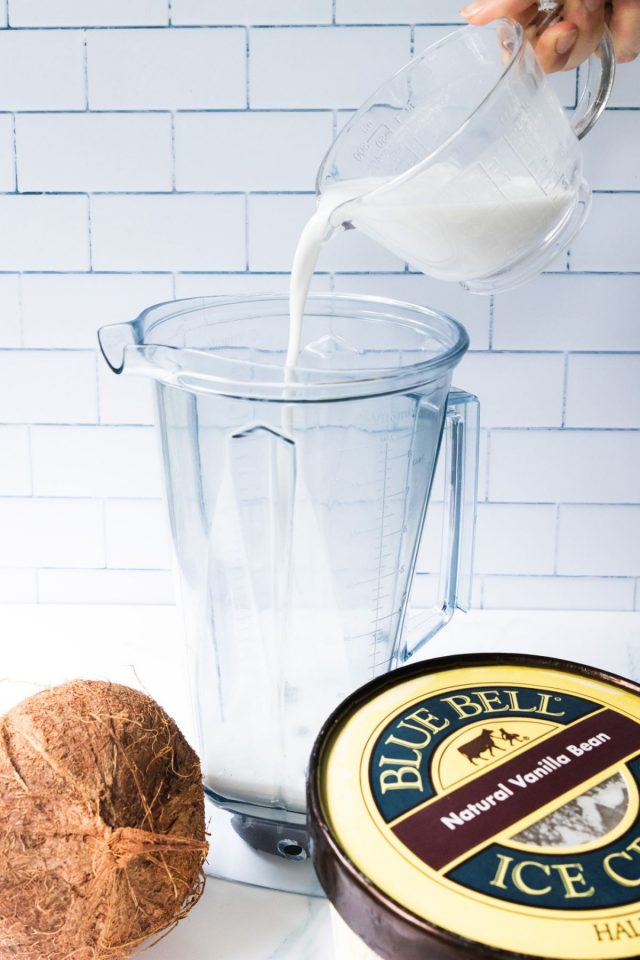 coconut cream milkshake - white liquid being poured in a jar blender