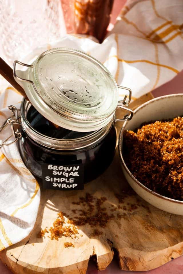 brown sugar simple syrup - black liquid in a jar beside a sugar