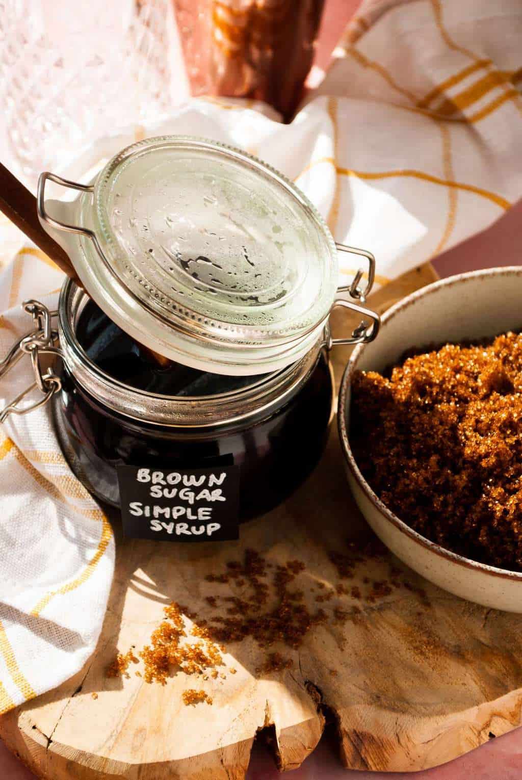 brown sugar simple syrup - black liquid in a jar beside a sugar