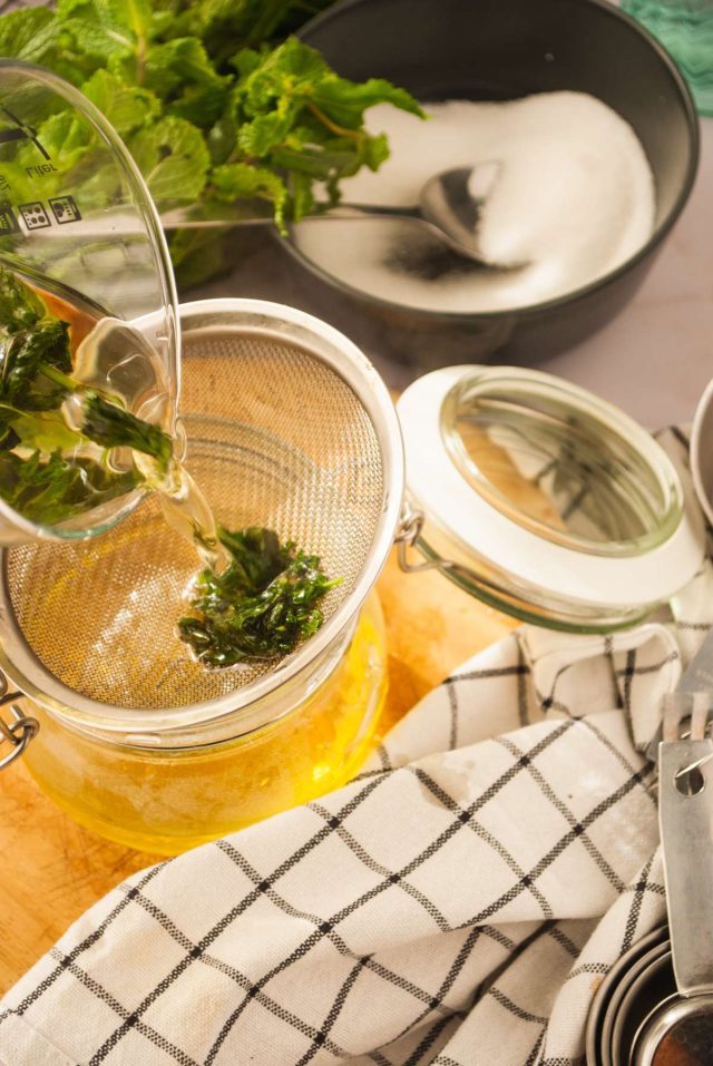 how to make mint simple syrup - pouring jar full of min tha water into a strainer