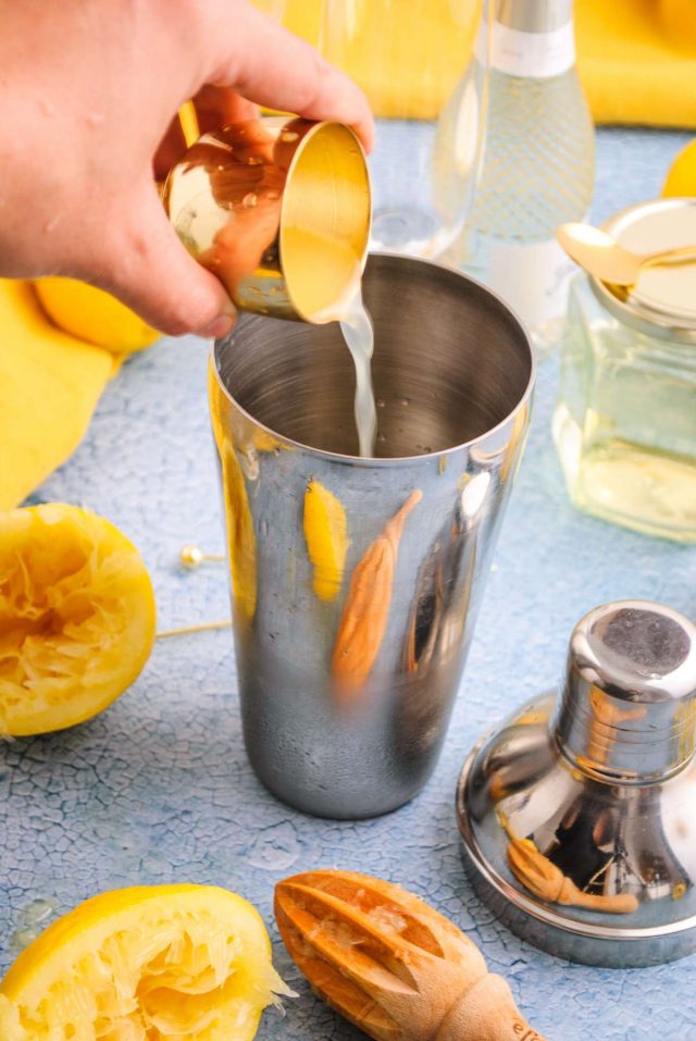 french 76 with vodka - pouring lemon juice in a cocktail mixer