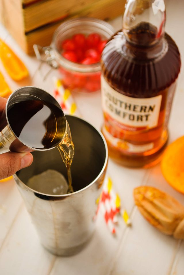 adding southern comfort in a cocktail shaker for the alabama slammer
