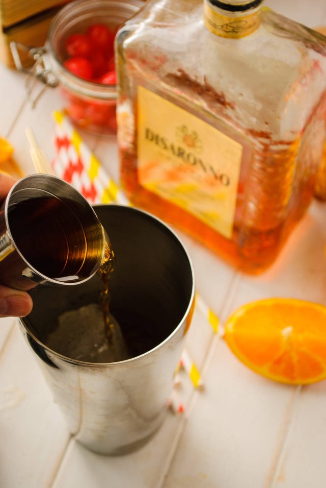adding liquor in a cocktail shaker for the alabama slammer