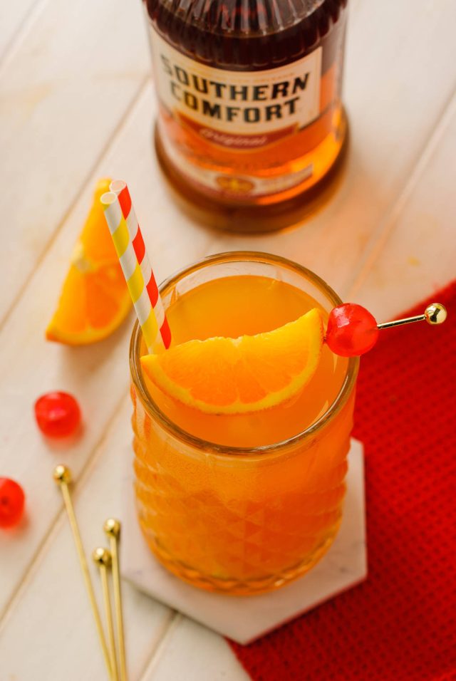 alabama slammer with cocktail pick with one orange wedge and a maraschino cherry