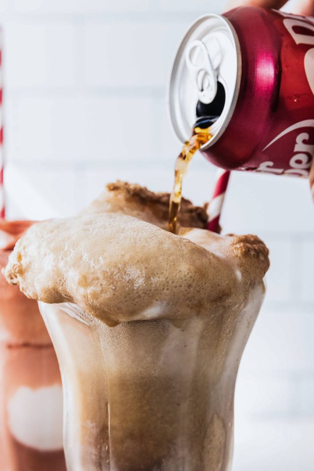 Pouring the chilled Dr. Pepper over the scoops of ice cream to create the float