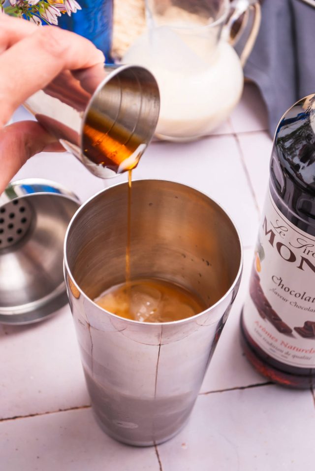 adding ingredients to the shaker for Brandy Alexander cocktail