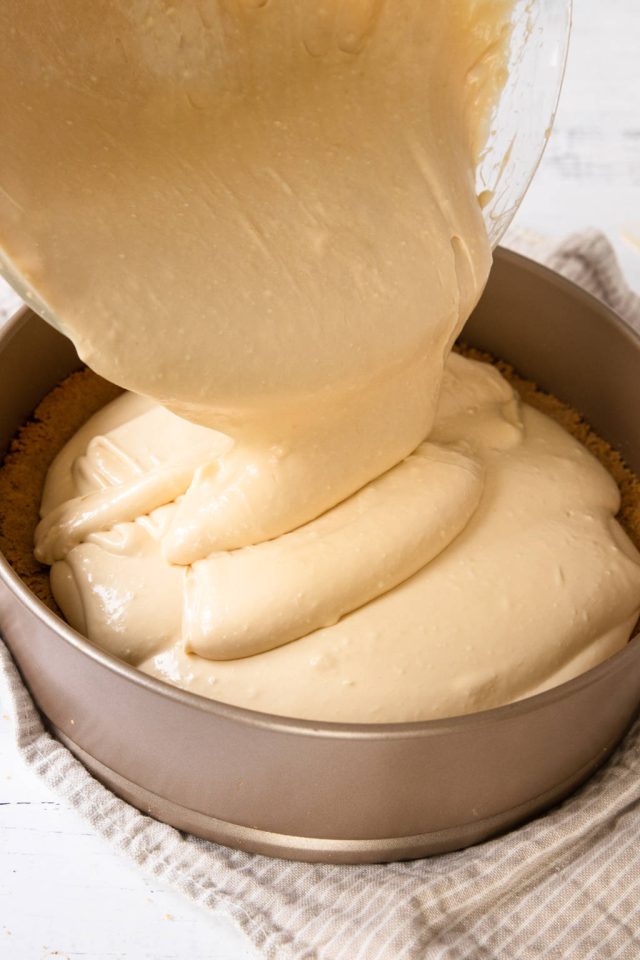 Pouring the cheesecake filling into the springform pan over the baked crust