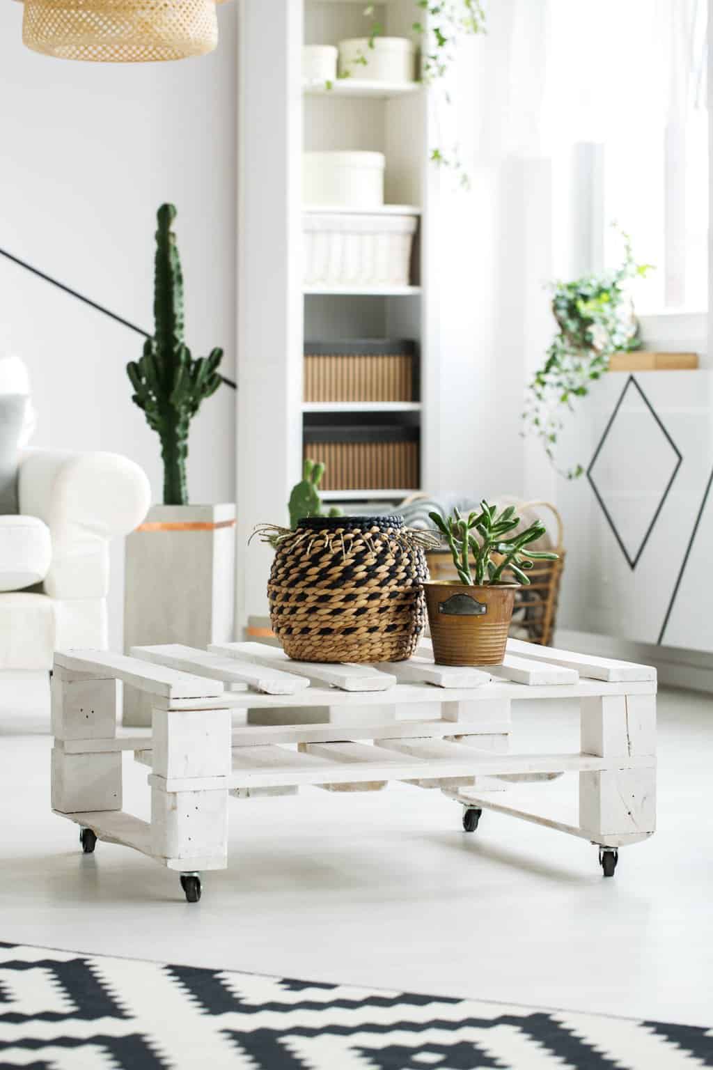 White wooden coffee table made of pallets with plants on it