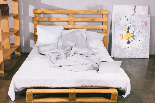 laptop on bed from wooden pallets in bedroom